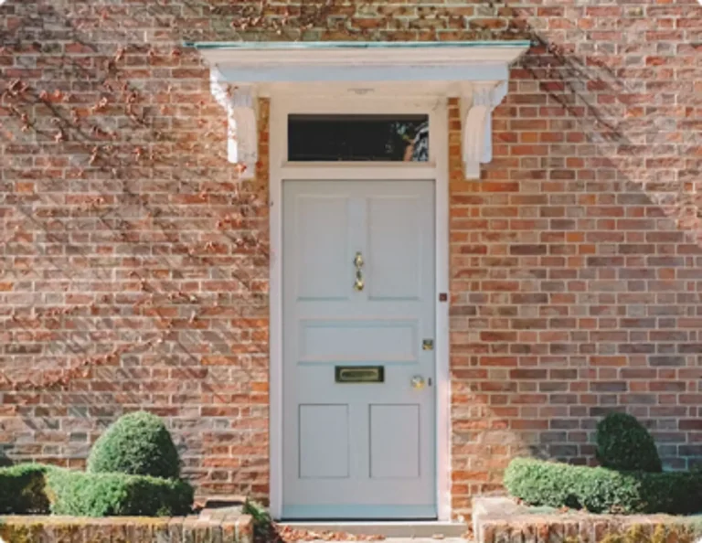 White front door with glass panels at a brick house